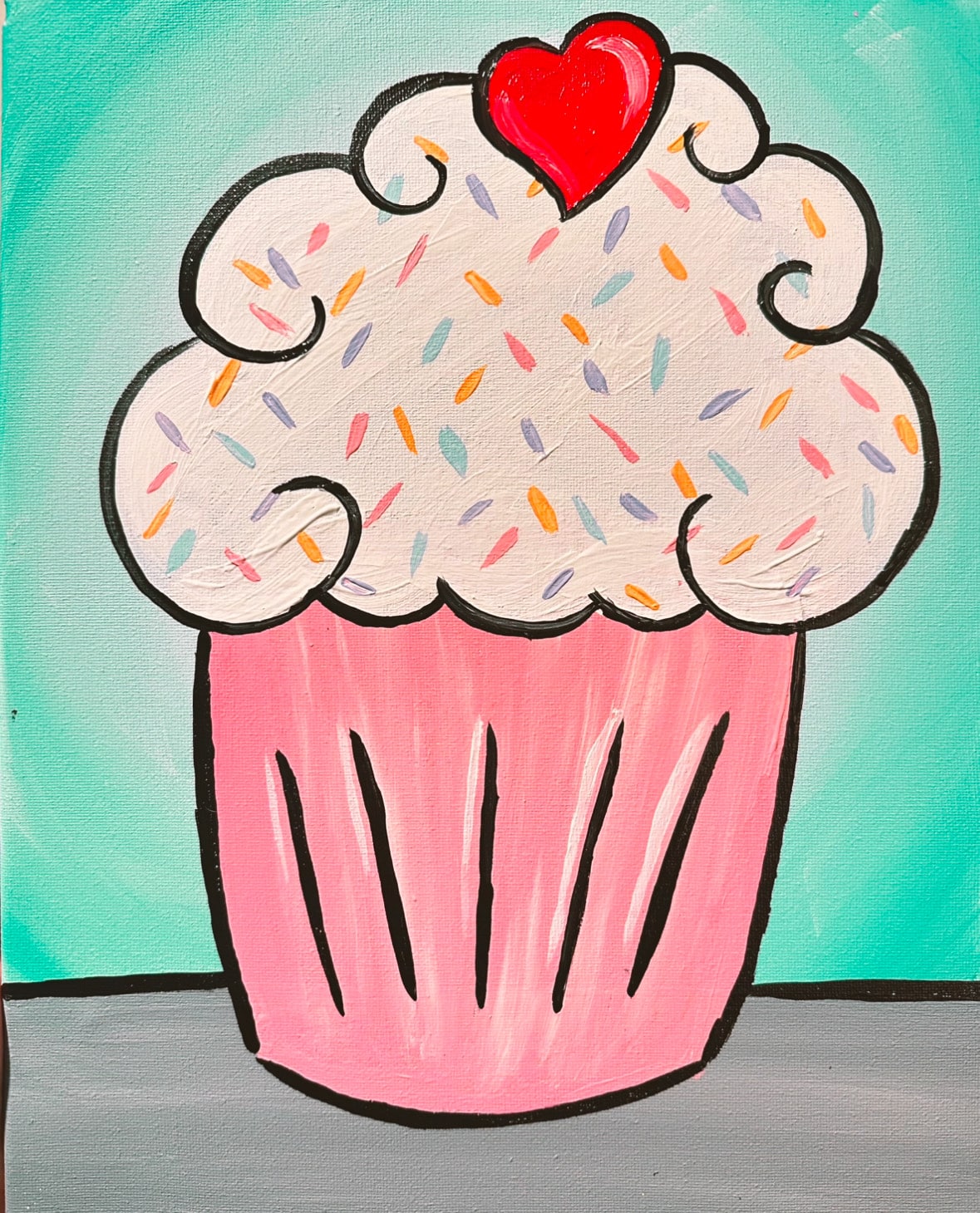 Colorful confetti cupcake with pink wrapper, white frosting, rainbow sprinkles, and a red heart on top, kids painting class artwork
