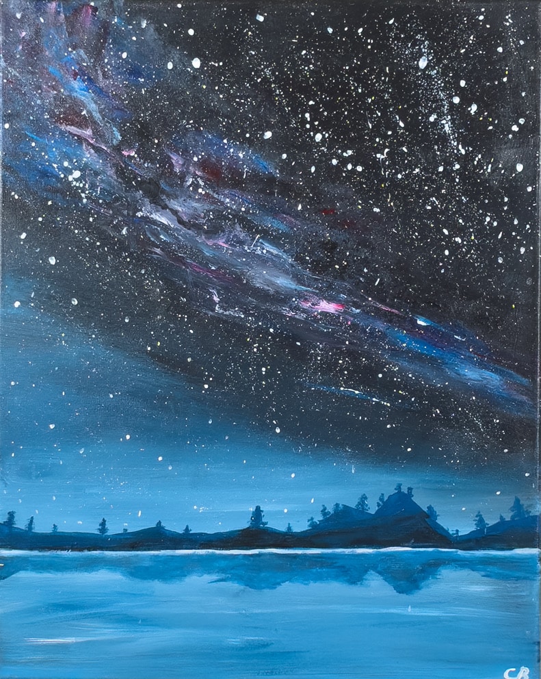 A star-filled night sky with a vibrant, colorful galaxy stretching overhead, reflected across a calm blue lake below, with dark silhouetted trees and hills along the horizon.