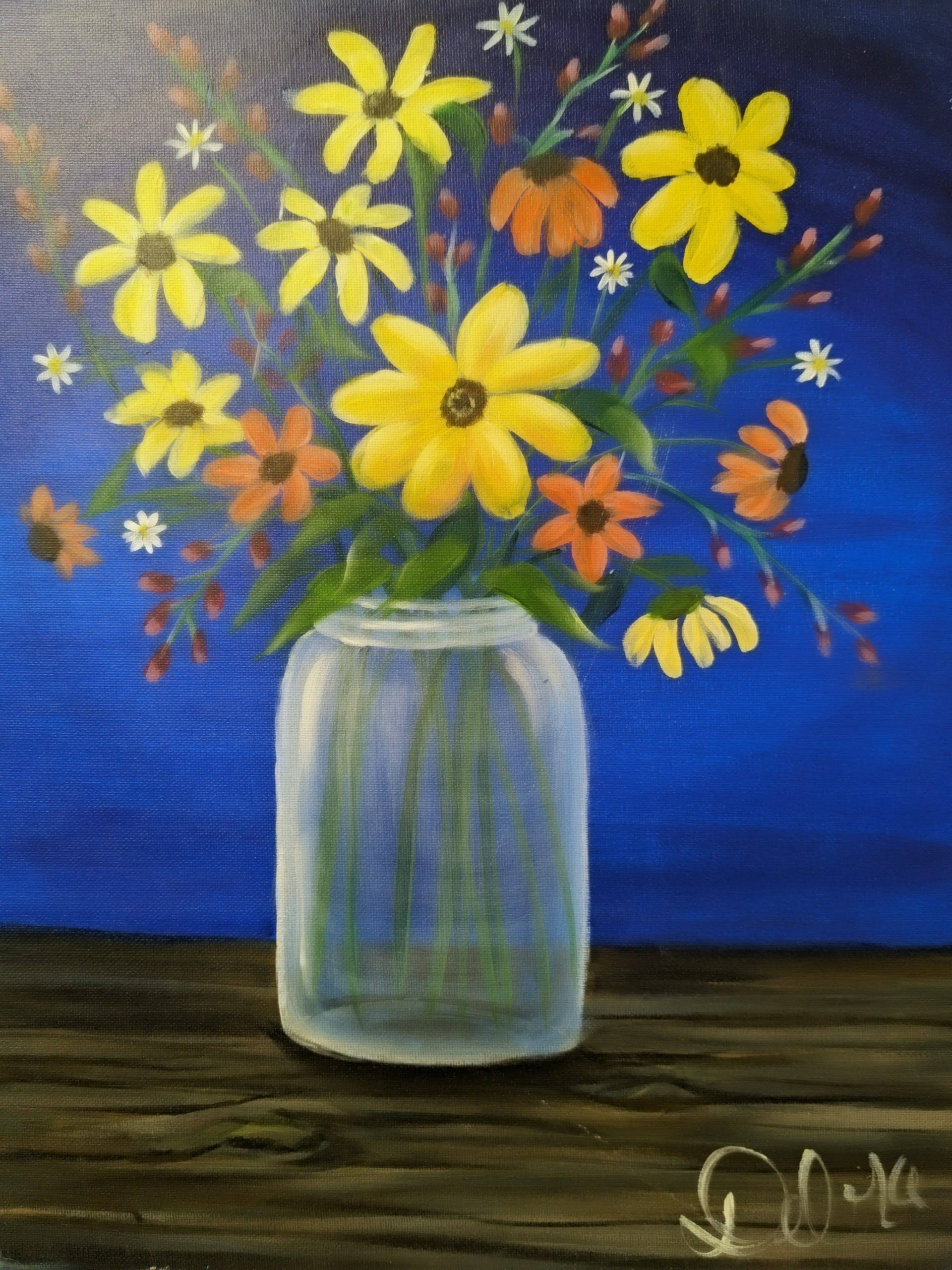 Colorful wildflowers in a glass mason jar on a wooden table with a blue background
