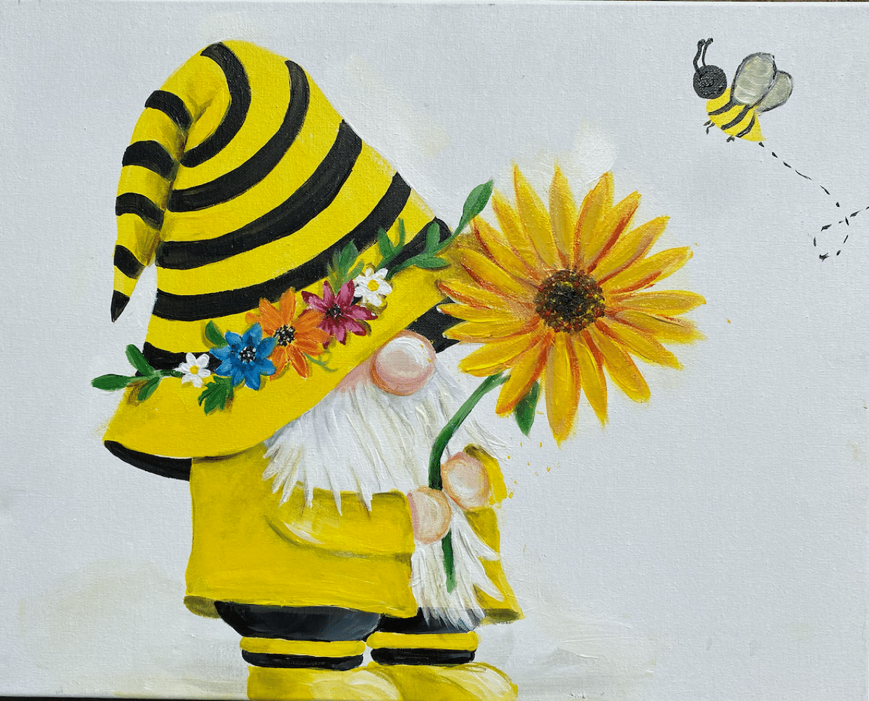 Bee-themed gnome wearing a striped yellow hat with flowers and holding a sunflower during a beginner-friendly Paint & Sip in Toledo.
