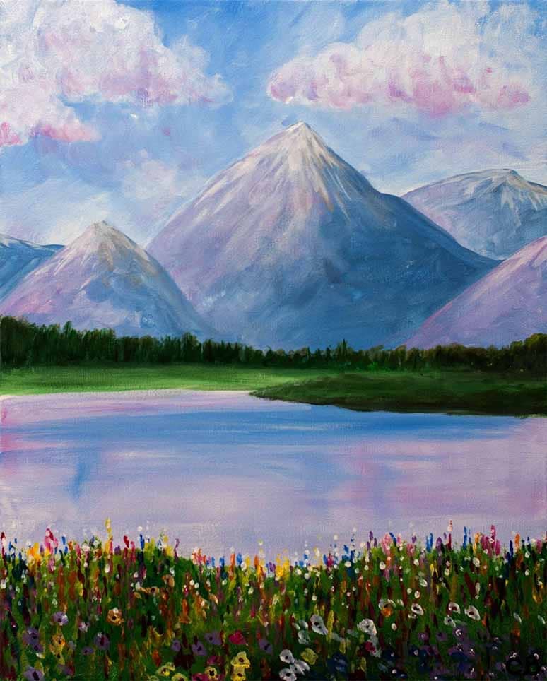 Peaceful mountain landscape featuring blooming wildflowers, a reflective lake, evergreen trees, and snow-capped mountains beneath soft clouds.